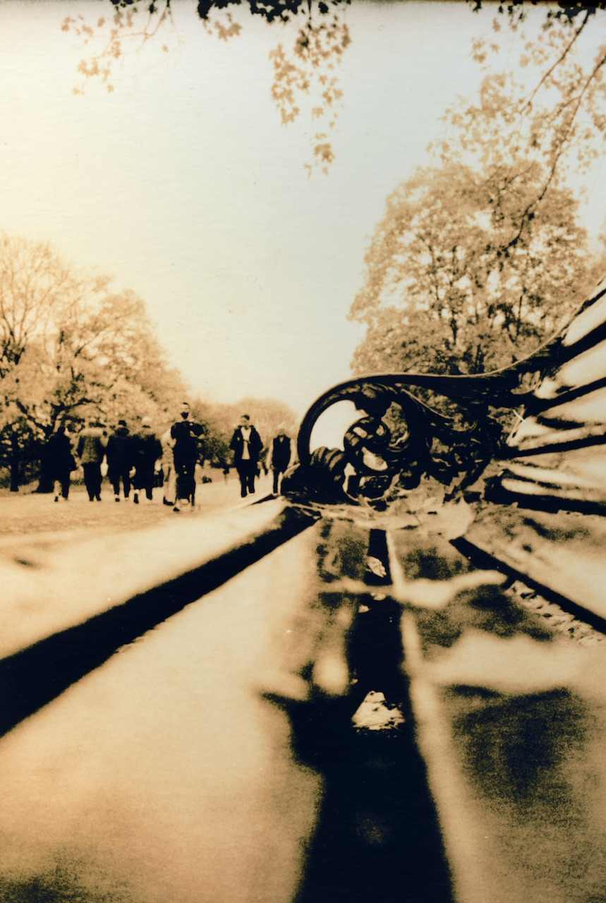 Soft warm lith print looking along a park bench in Hyde Park, London