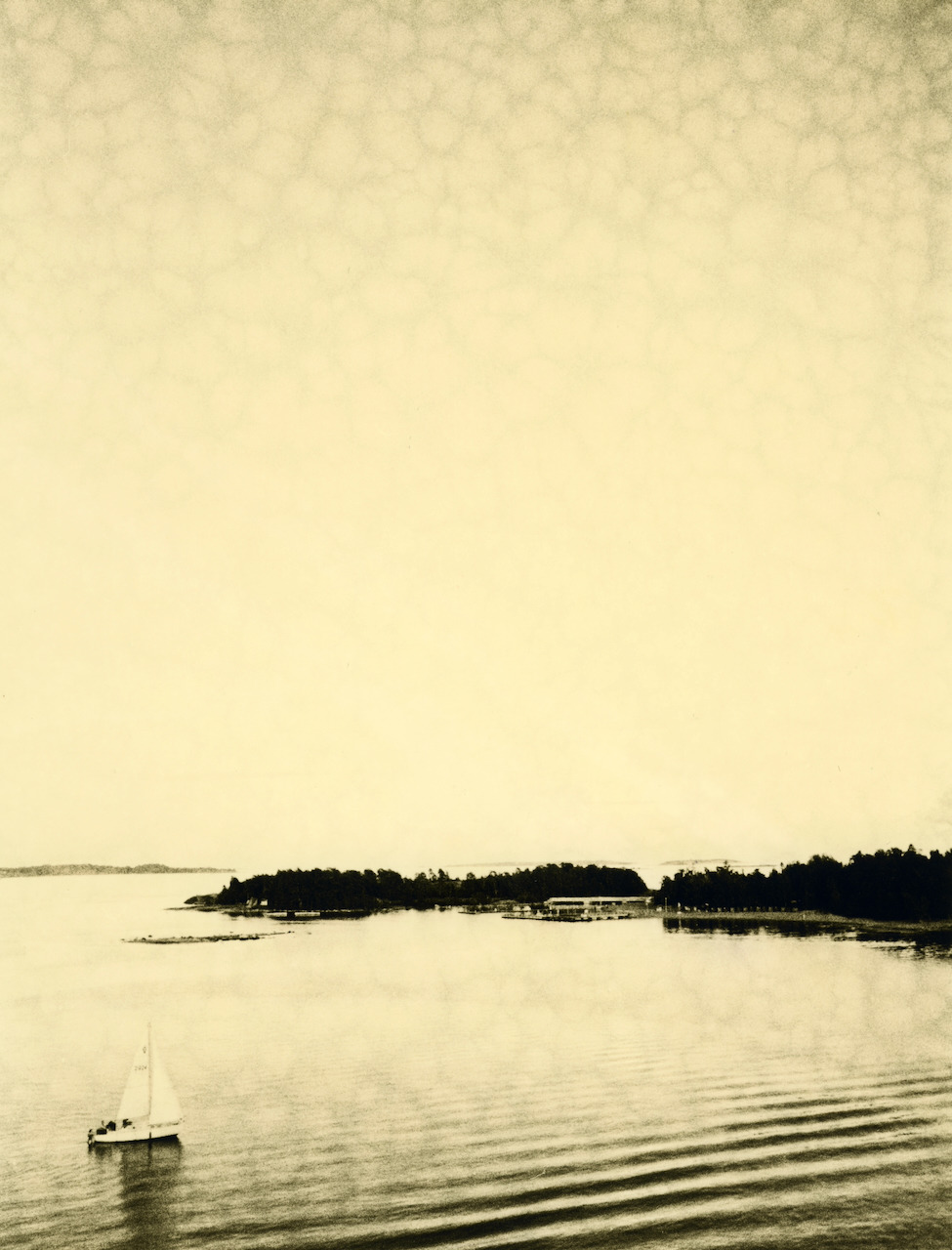 Warm lith print of a sailing boat, with faint mottling across the pale sky