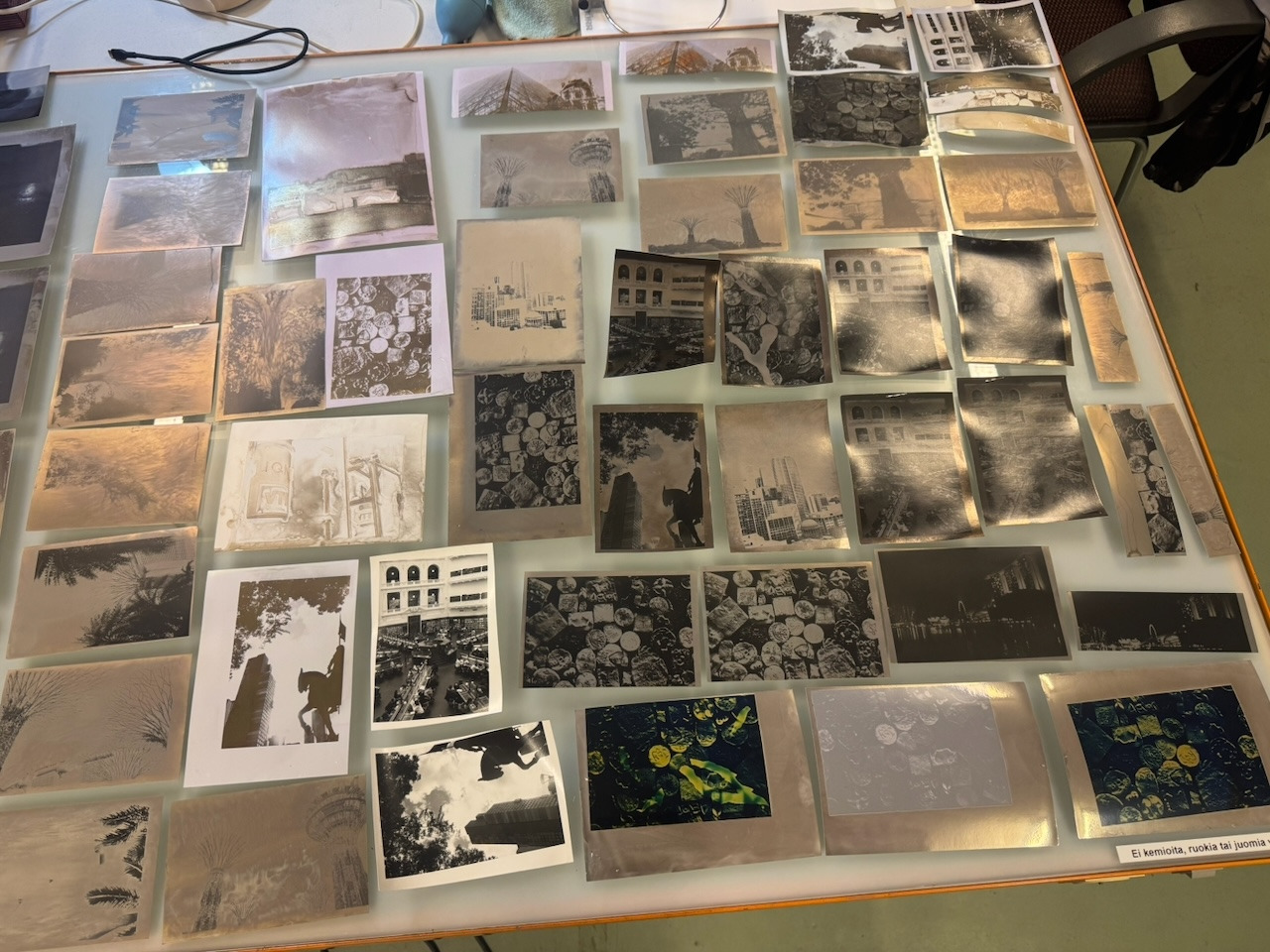 A light table covered in silver mirror toned prints, photographed from directly above