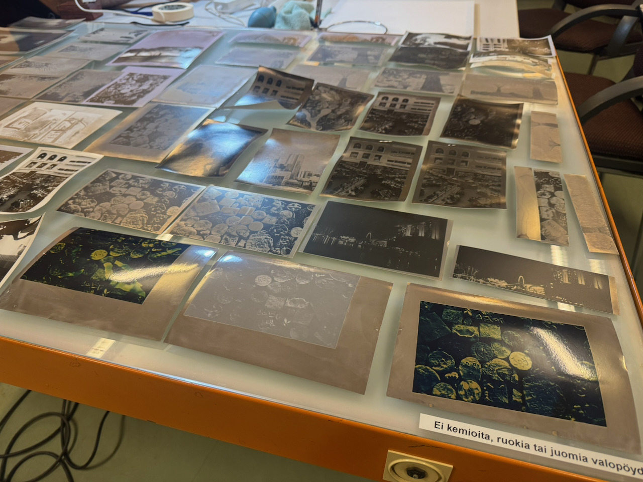 The same light table photographed at a low angle, with several prints flaring metallically